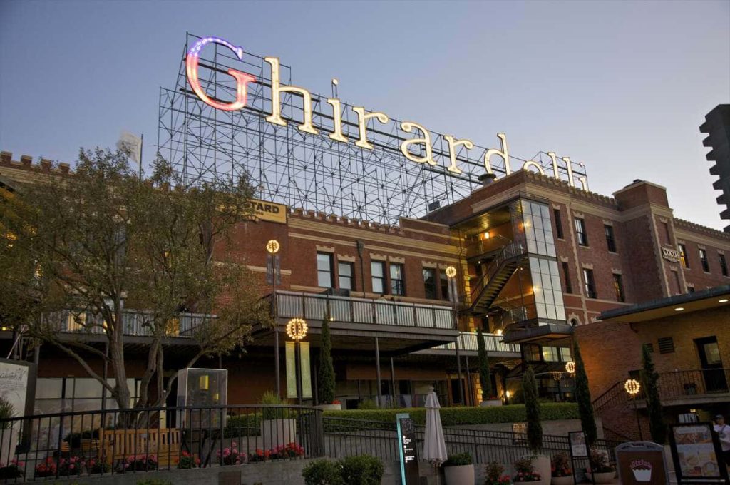 Ghirardelli Square San Francisco red brick landmark glowing at twilight with illuminated sign background Wallpaper
