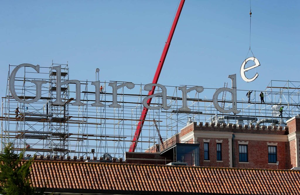 Restoration of Ghirardelli Square sign with crane and crews on scaffolding against blue sky Wallpaper