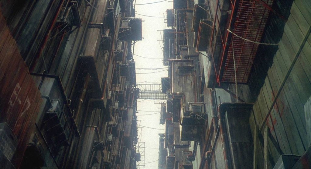 Low-angle urban dystopian scene from Ghost in the Shell anime with layered industrial buildings wallpaper