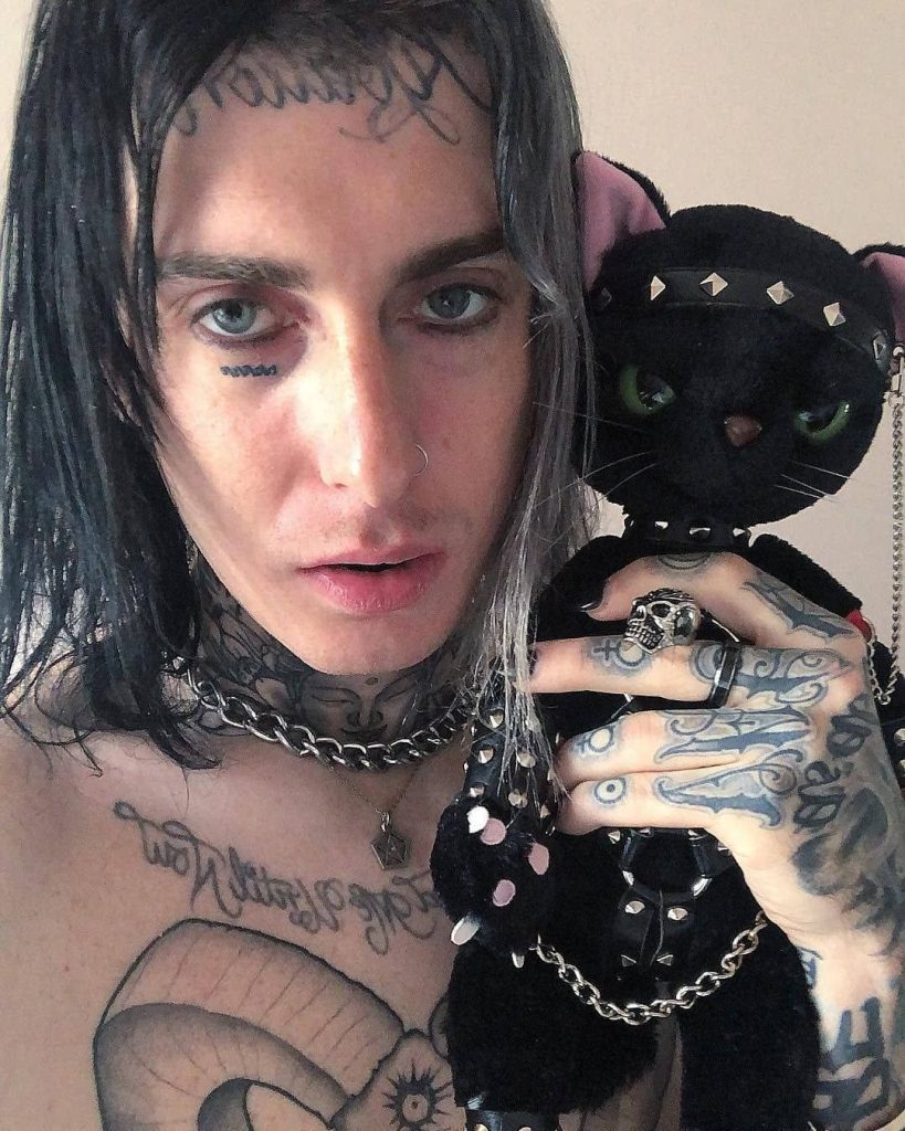 Ghostemane close-up with tattoos chains holding dark studded black cat plushie gothic wallpaper
