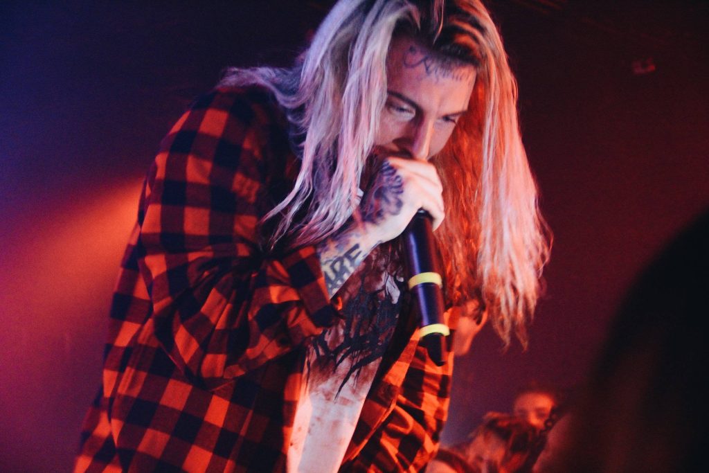 Ghostemane performing live in red black flannel with tattoos under moody red stage lighting wallpaper