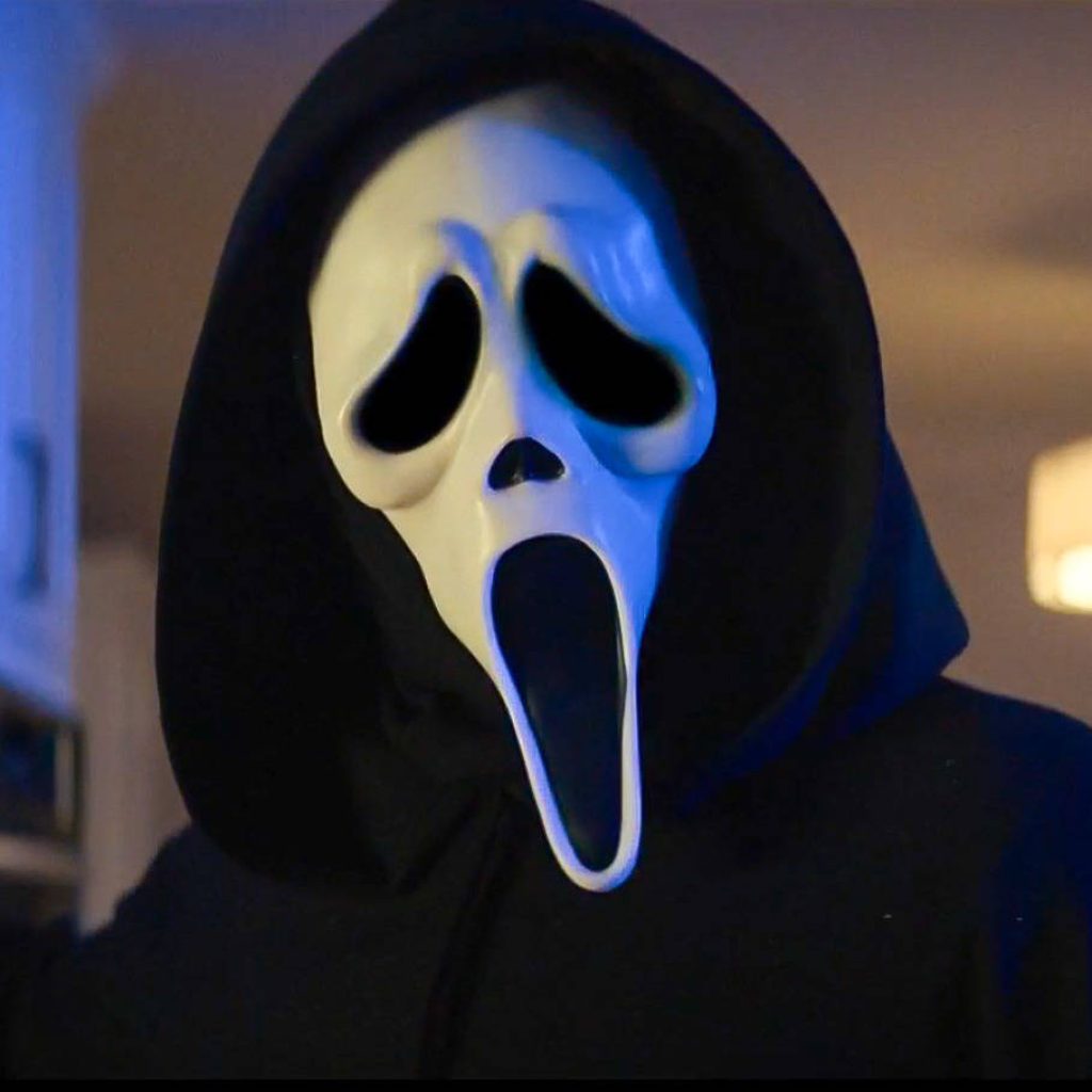 Ghostface killer from Scream in white mask and black hood with moody horror lighting background Wallpaper