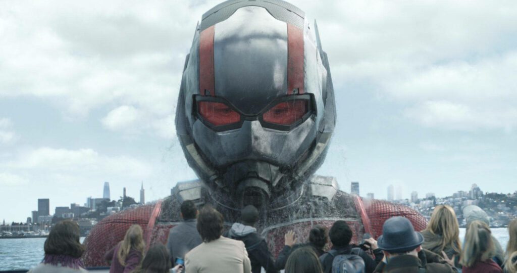Giant Ant Man rises from water towering over crowd city skyline wallpaper background scene