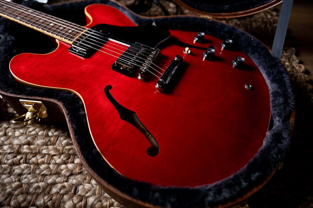 Close-up of Gibson ES-335 guitar in cherry finish with chrome hardware and f-holes in black case Wallpaper