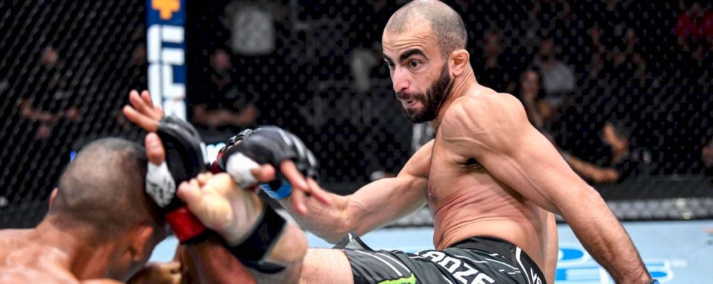 UFC fighter Giga Chikadze delivers a high kick in the octagon intense MMA action wallpaper