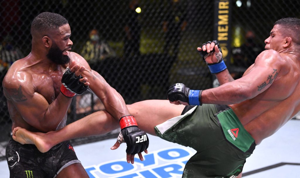 Gilbert Burns delivering a powerful kick to Tyron Woodley in intense UFC fight action wallpaper