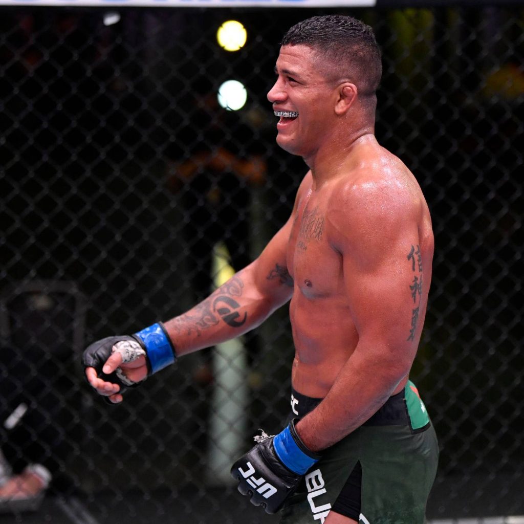 Gilbert Burns smiling side profile in UFC octagon wearing blue gloves green shorts MMA action Wallpaper