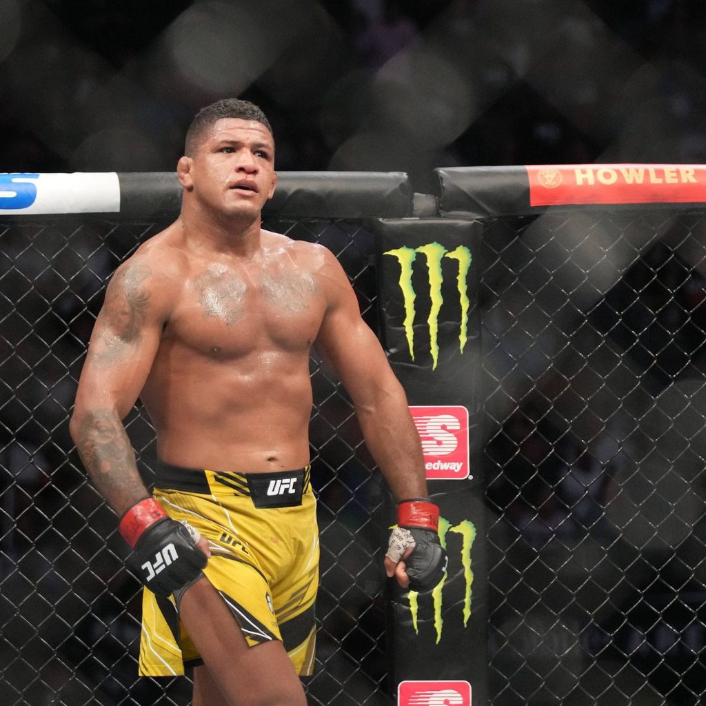 Gilbert Burns in yellow shorts inside UFC Octagon showing intense focus and muscular strength Wallpaper