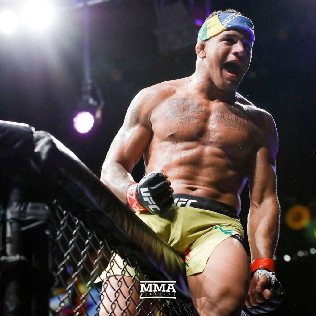 Gilbert Burns UFC victory shout MMA intense fight celebration Octagon fence arena lighting Wallpaper