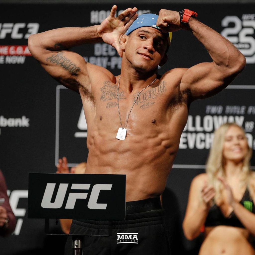 UFC fighter Gilbert Burns flexing muscles shirtless at weigh-in wearing star-patterned beanie Wallpaper