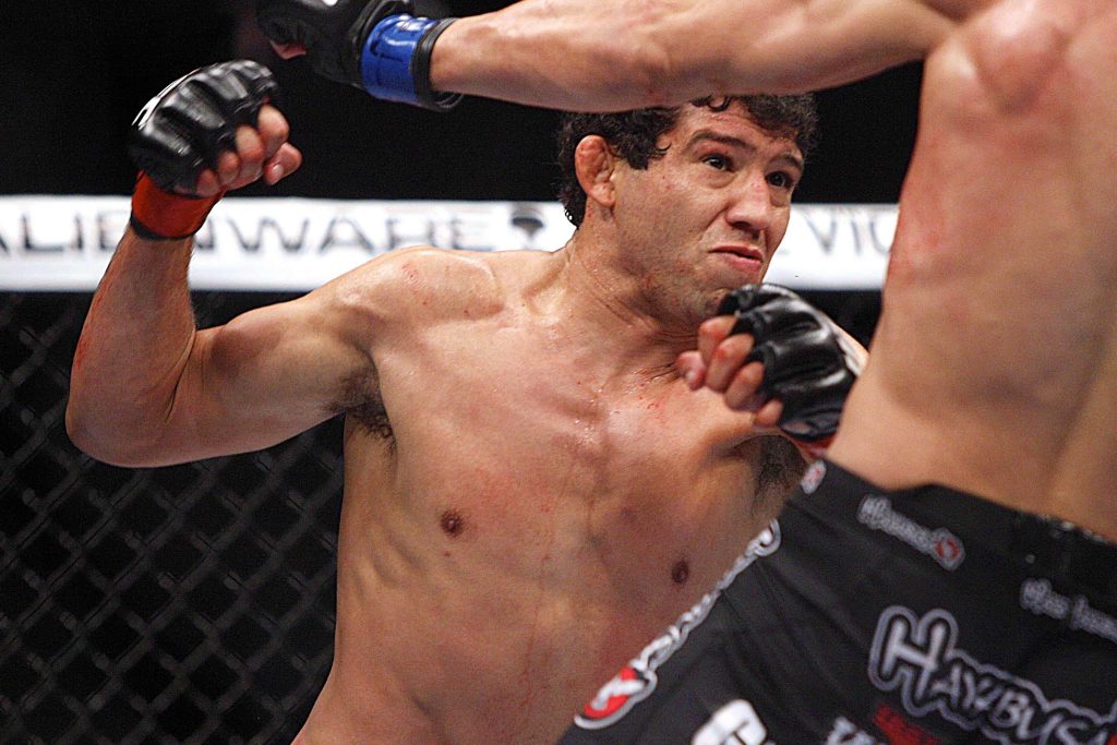 Gilbert Melendez MMA fighter delivering powerful strike inside cage with intense arena lighting Wallpaper