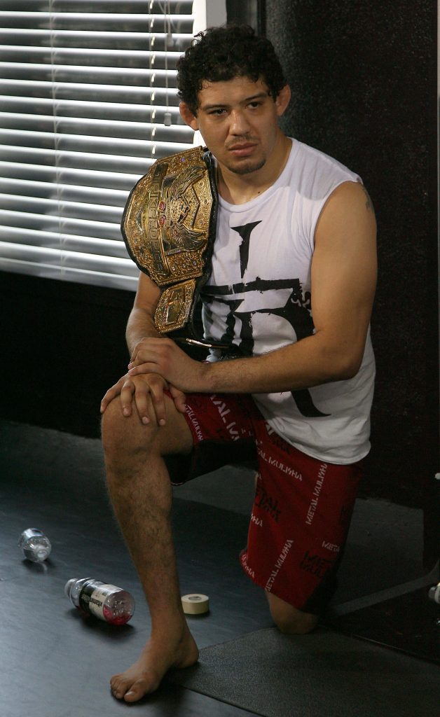 MMA champion Gilbert Melendez kneeling in gym with gold Strikeforce Lightweight title belt Wallpaper