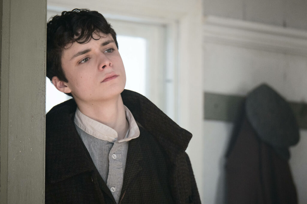 Gilbert from Anne with an E in vintage attire pensively leaning on doorframe reflective mood wallpaper