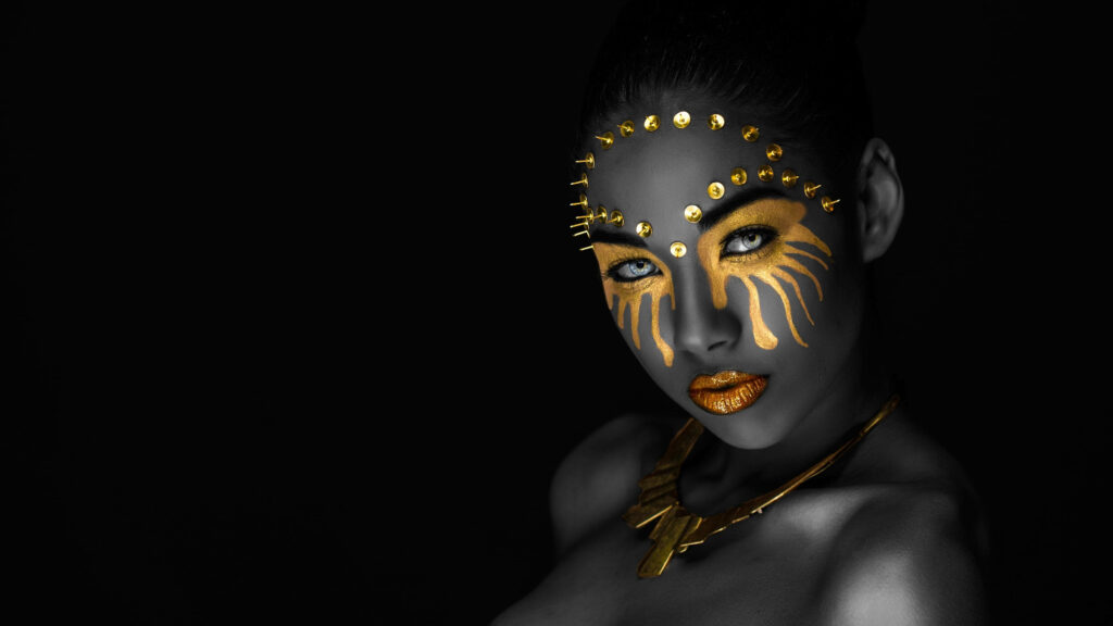 Glamorous Goddess: A Stunning Portrait of a Black Woman Adorned in Bold Gold Makeup and Intricate Accessories Wallpaper