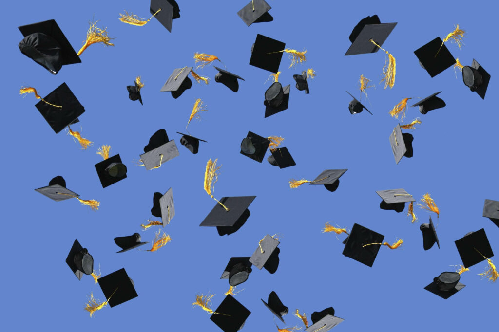 Achieving Dreams: Majestic Graduation Caps Soaring Against the Cloudless Sky Wallpaper