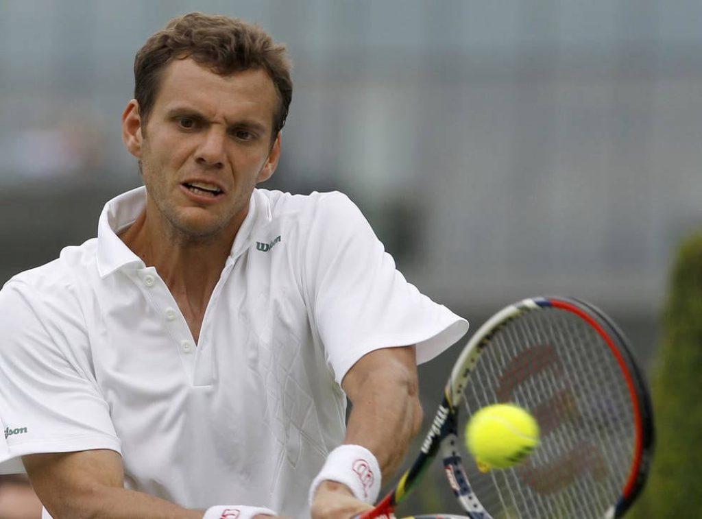 Gilles Simon mid-swing hitting yellow tennis ball with Wilson racket intense tennis action wallpaper
