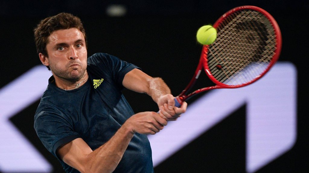 Gilles Simon hitting powerful backhand with red racquet at Australian Open tennis court wallpaper