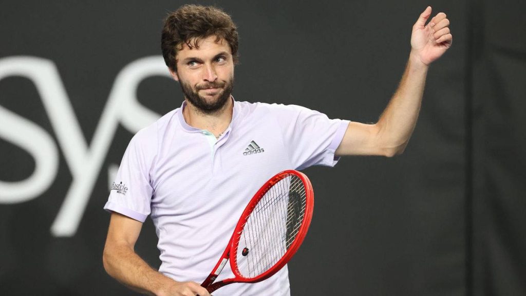 Tennis star Gilles Simon in purple Adidas shirt with red racket giving thumbs-up on dark background Wallpaper