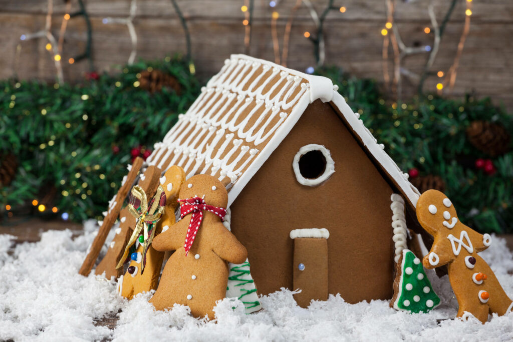 Frosty Friends: Cheery Gingerbread Men Gather by the Festive Cookie House Amidst a Snowy Surrounding Wallpaper