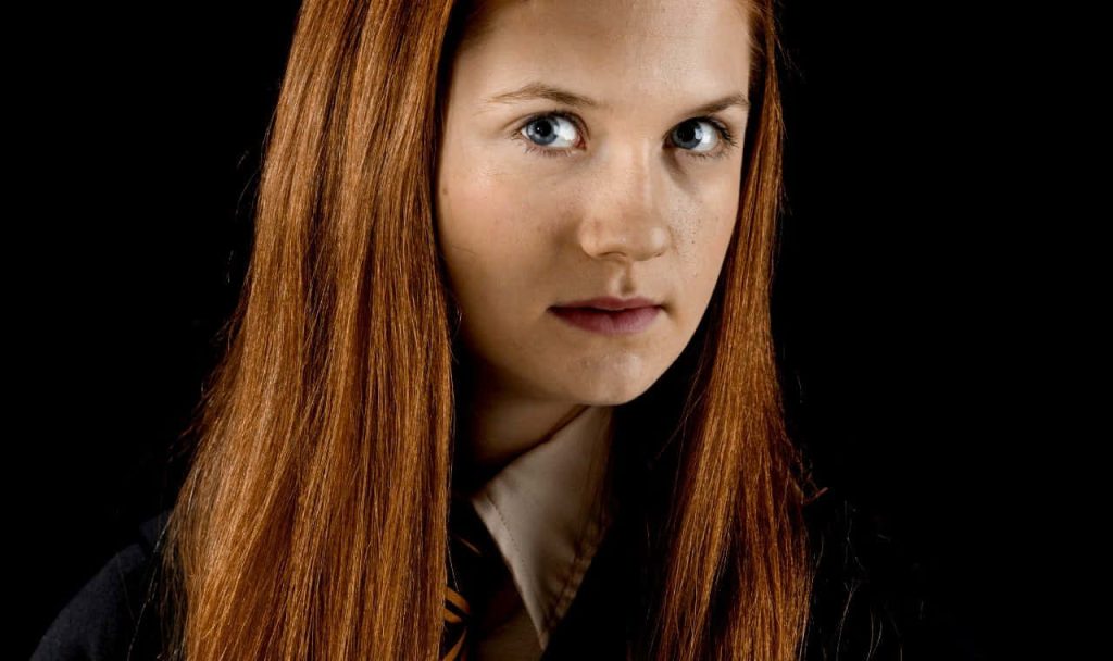 Close-up of Bonnie Wright as Ginny Weasley in Gryffindor uniform black background wallpaper