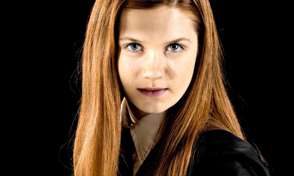 Portrait of Ginny Weasley in Gryffindor uniform with long red hair and blue eyes on black background Wallpaper
