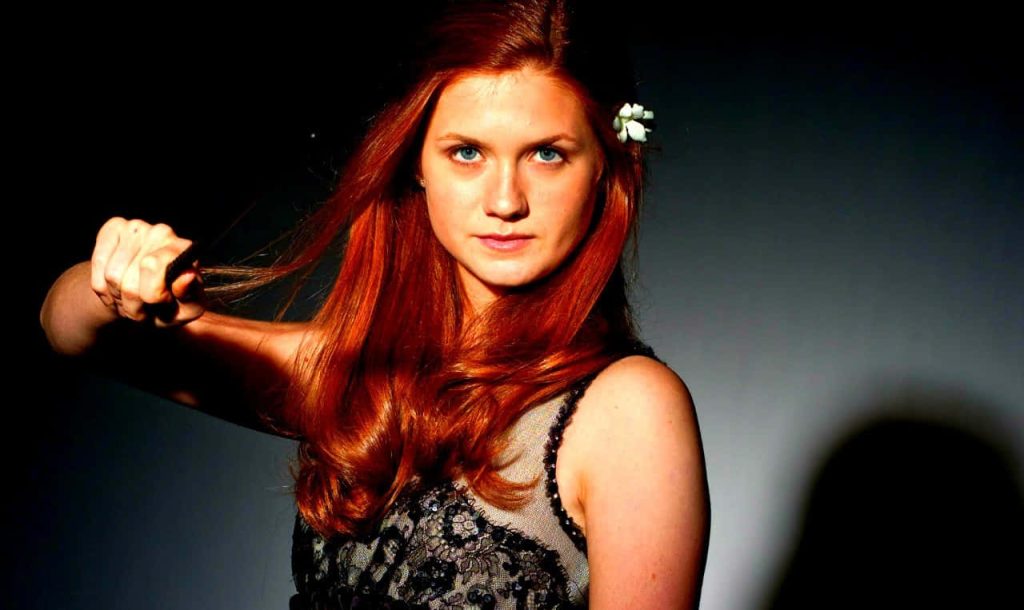 Bonnie Wright as Ginny Weasley vibrant red hair white flower dark lace confident gaze wallpaper