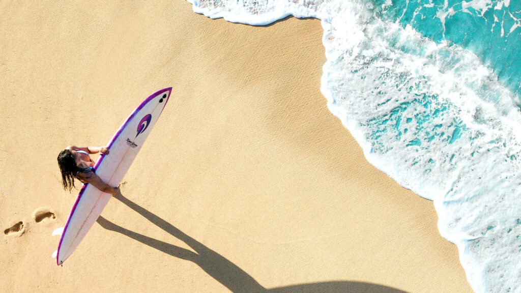 Girl with Surfboard on Sandy Beach, Ready for Ocean Waves Wallpaper