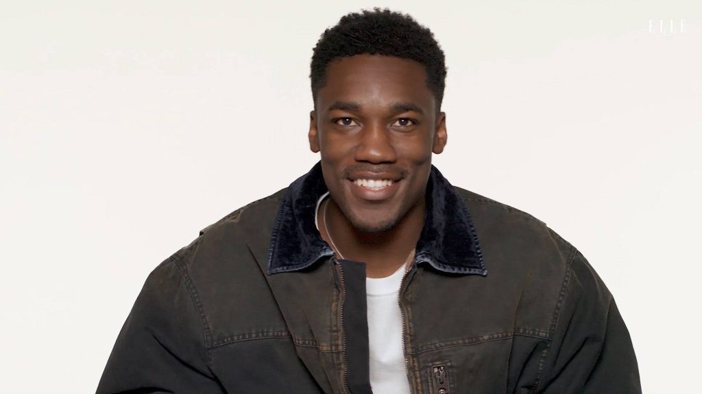 Giveon R&B singer portrait smiling in dark shearling jacket white tee studio photo Elle magazine Wallpaper