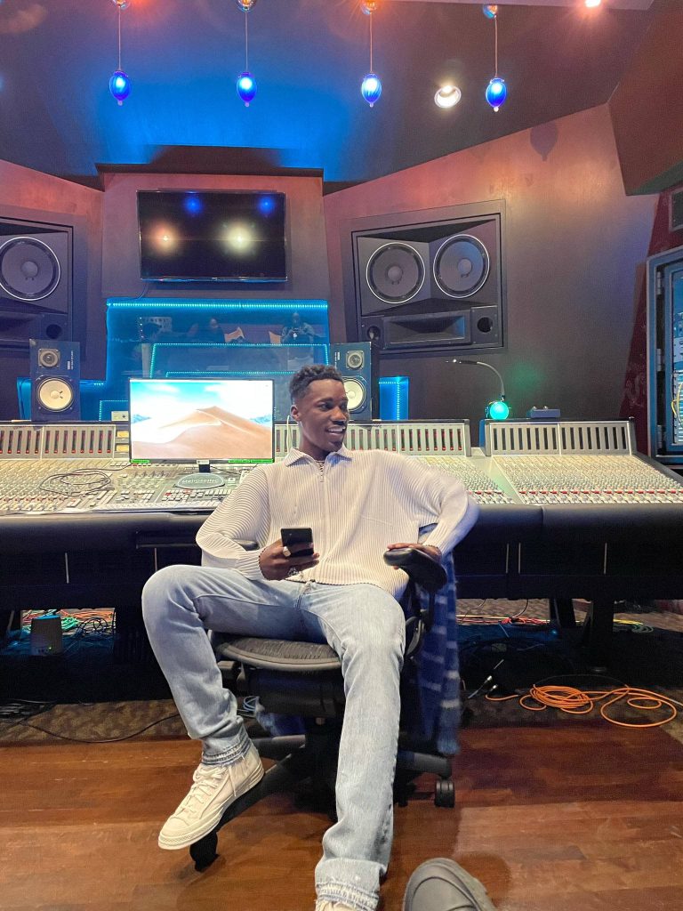 R&B singer Giveon in blue-lit professional recording studio with large mixing console background Wallpaper