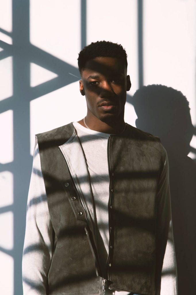 Giveon R&B artist high-fashion portrait with window shadow art on white wall background Wallpaper