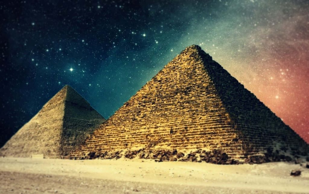 Giza Pyramids illuminated under vibrant galaxy night sky with stars and nebulae digital art Wallpaper
