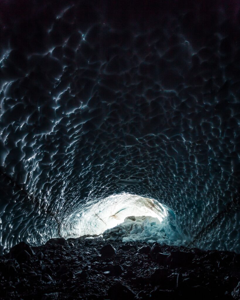 Stunning glacier cave interior with blue ice patterns illuminated by natural light wallpaper background