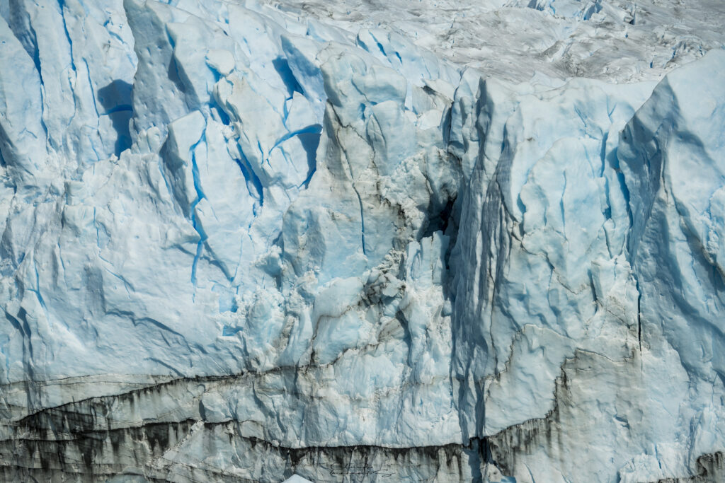 Striking glacier ice wall wallpaper with rugged blue and white relief patterns and jagged rocks