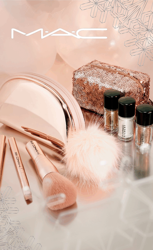 Glamorous MAC makeup set with gold brushes sparkling pigments and festive snowflake background Wallpaper