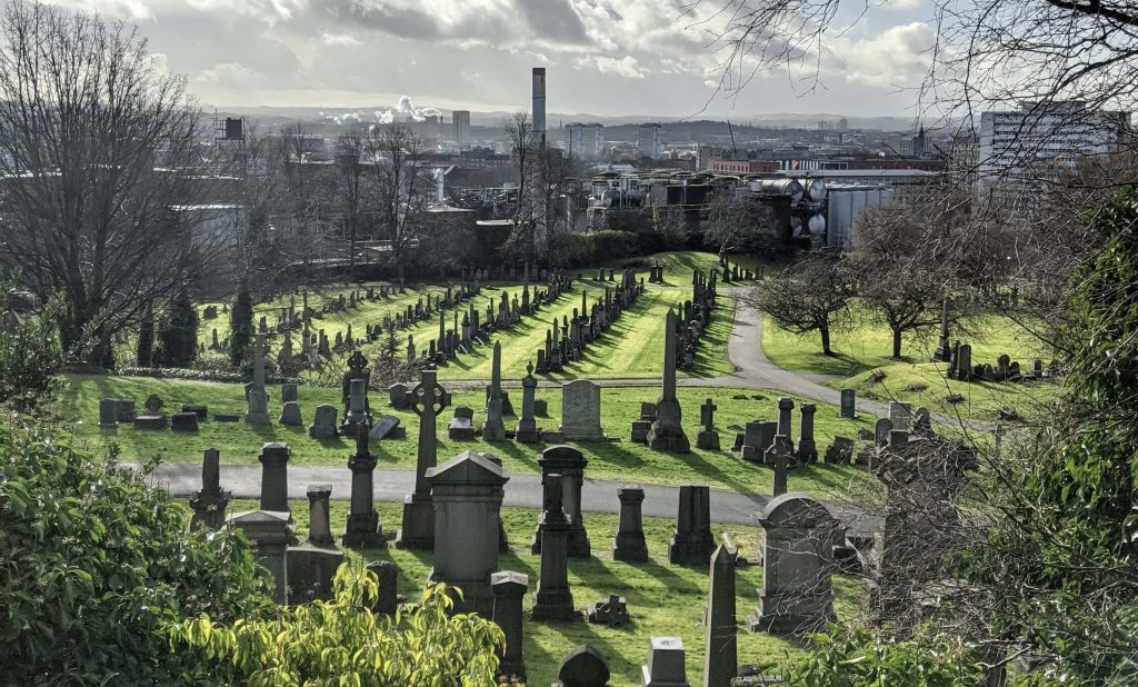 Glasgow Necropolis historic gravestones and monuments on green hillside with city skyline background Wallpaper