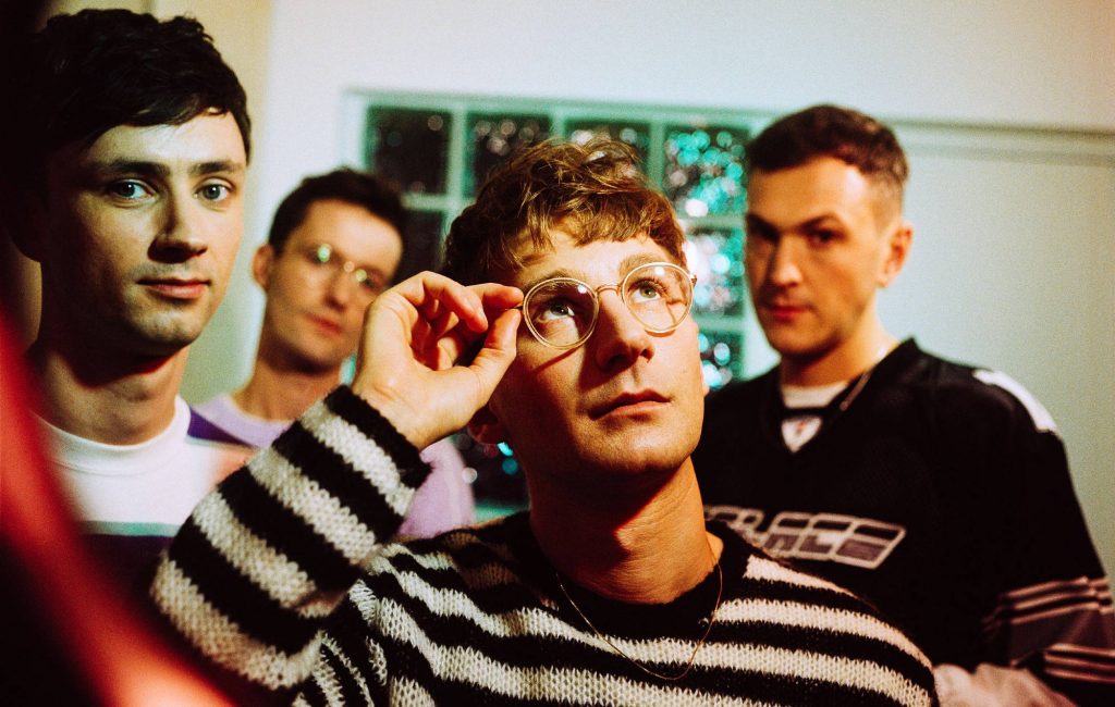 Glass Animals band mirror reflection with lead singer adjusting glasses vintage cinematic light Wallpaper