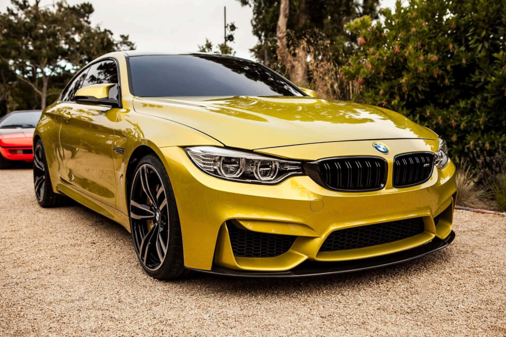 Gleaming Gold BMW on Arid Terrain: An Alluring Snapshot of Luxury Car Prestige Wallpaper