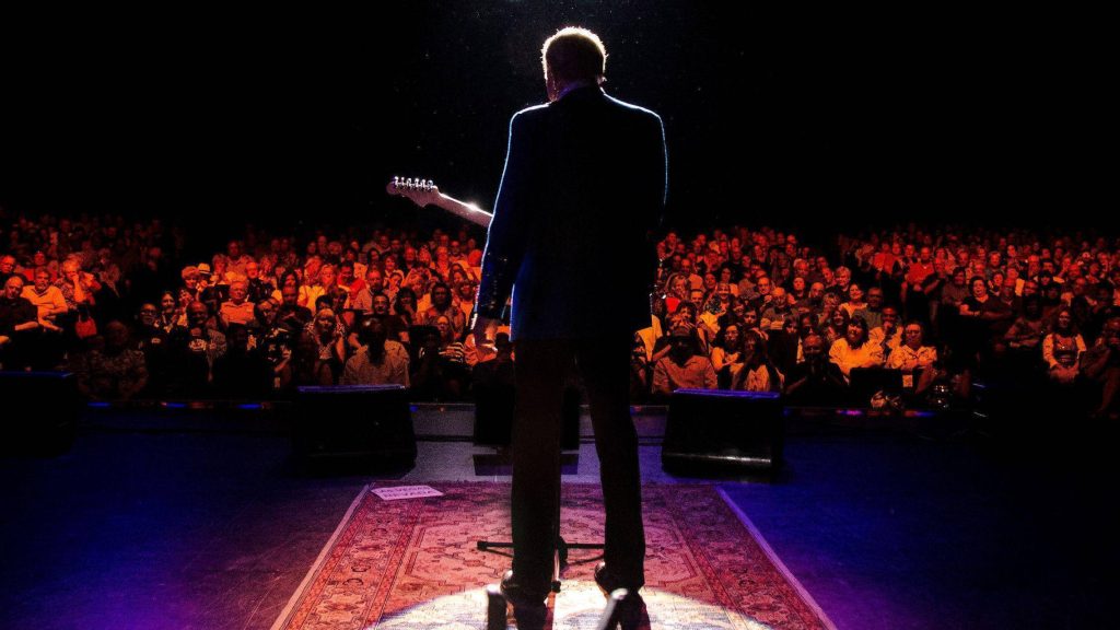 Glen Campbell silhouette on stage spotlight performing live concert with audience view wallpaper