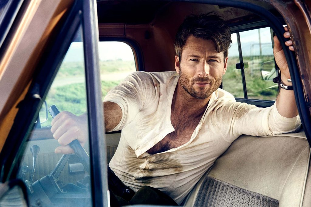 Glen Powell seated in vintage truck with sunlit rustic rural landscape portrait wallpaper