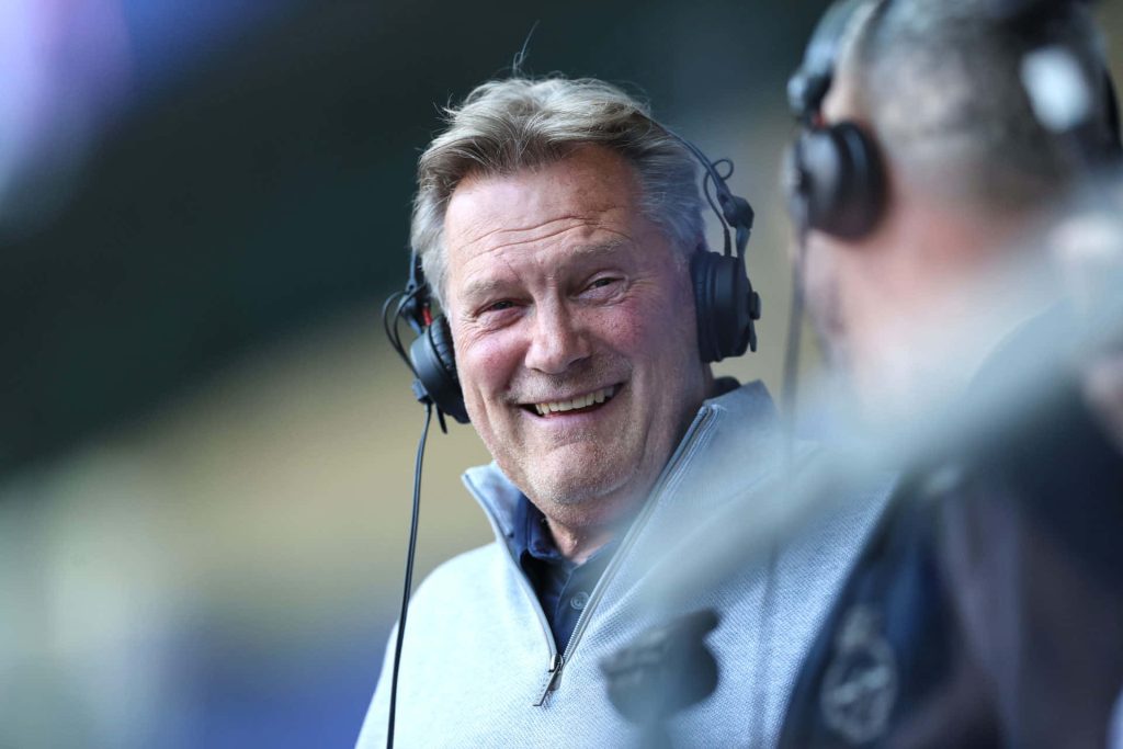 Glenn Hoddle smiling with broadcast headphones in gray sweater stadium lighting portrait wallpaper