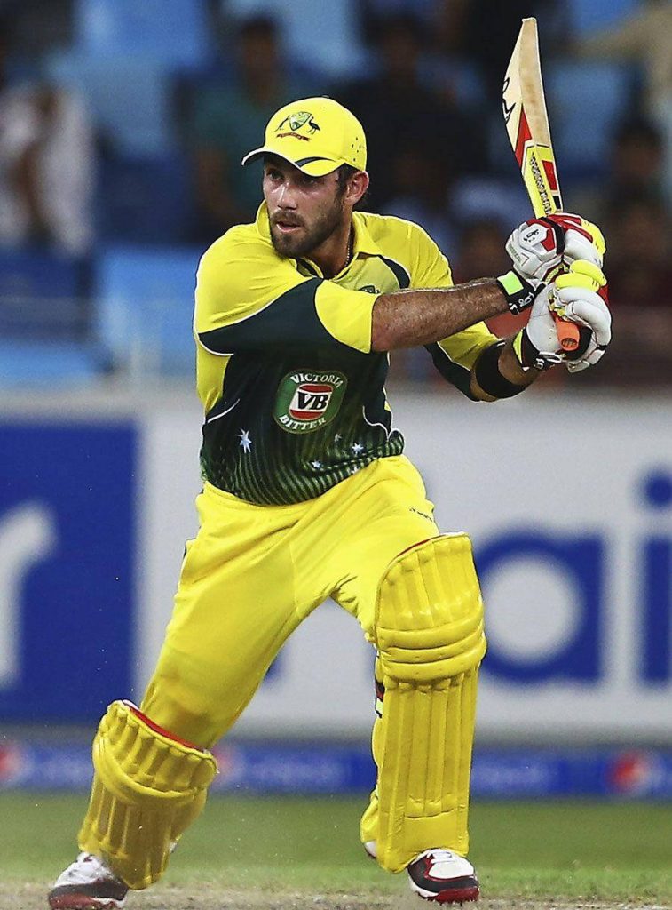 Glenn Maxwell batting in Australian cricket uniform with vibrant stadium lights background wallpaper