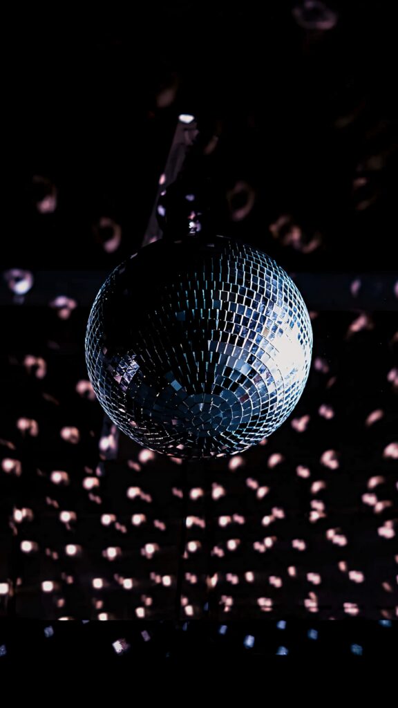Glimmering disco ball reflecting sparkling lights in dark room vibrant nightlife wallpaper background
