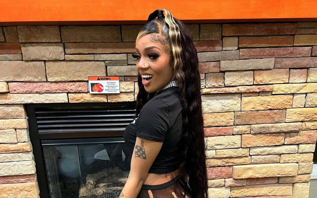 GloRilla vibrant wallpaper rapper smiling stone fireplace long dark hair blonde highlights stylish flair