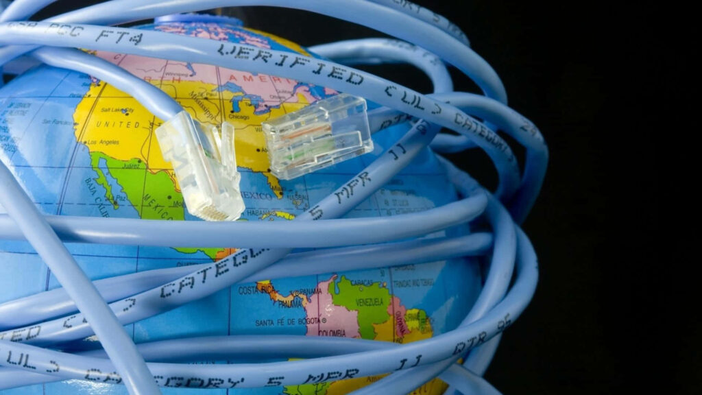 Bright blue Ethernet cable wrapped around colorful globe symbolizing global connectivity and technology Wallpaper