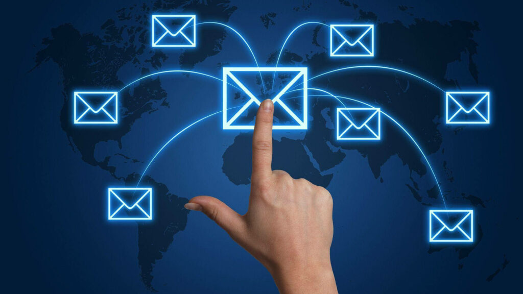 Hand pressing glowing email icon with connected envelopes over world map digital wallpaper background