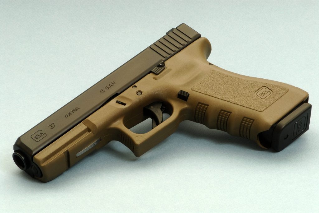 High-resolution studio image of Glock 37 pistol tan polymer frame dark slide on neutral background Wallpaper