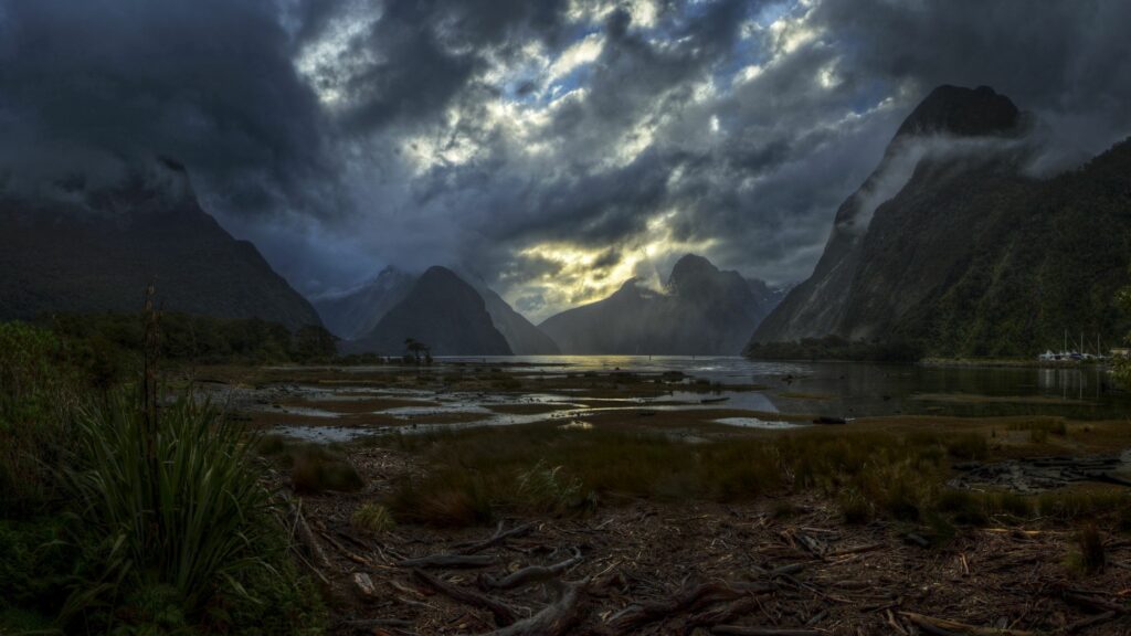 Gloomy sky over rugged mountains with twisted roots and dark wild landscape wallpaper background