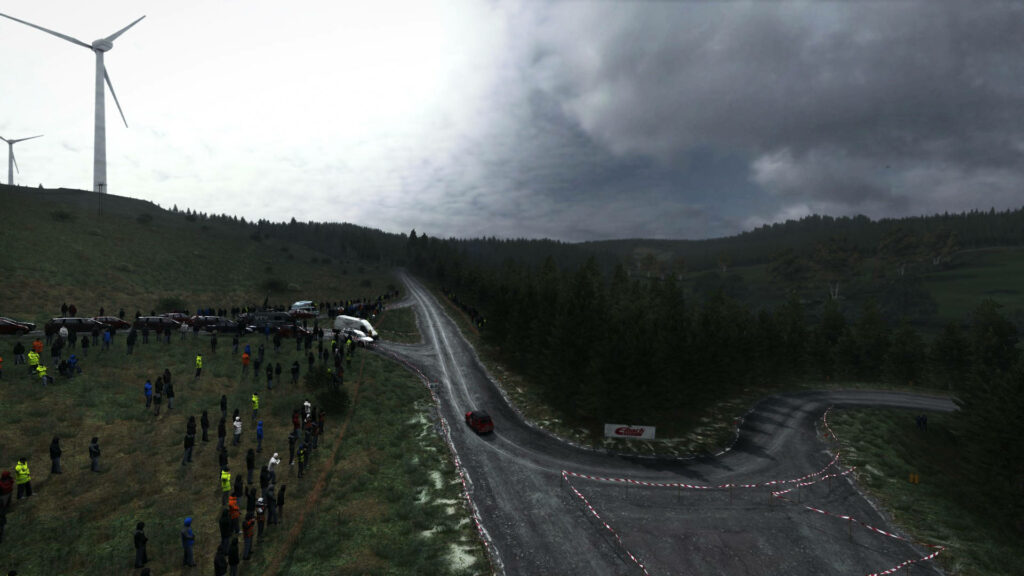 Exciting Dirt Rally Event Wallpaper: Speeding Car, Forests, Spectators, Turbines