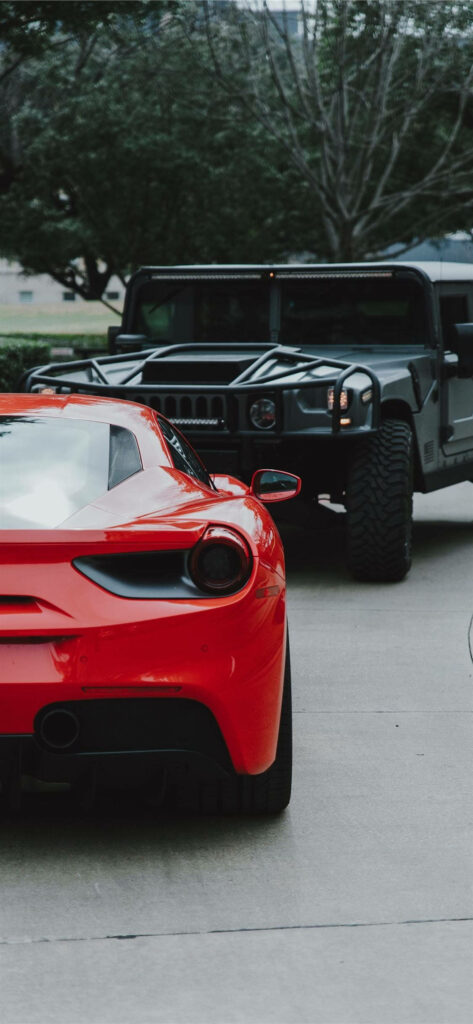 Powerful Rides: A Striking Red Hummer H1 Leading the Pack, Parked Gracefully with a Black Humvee, Surrounded by Nature Wallpaper