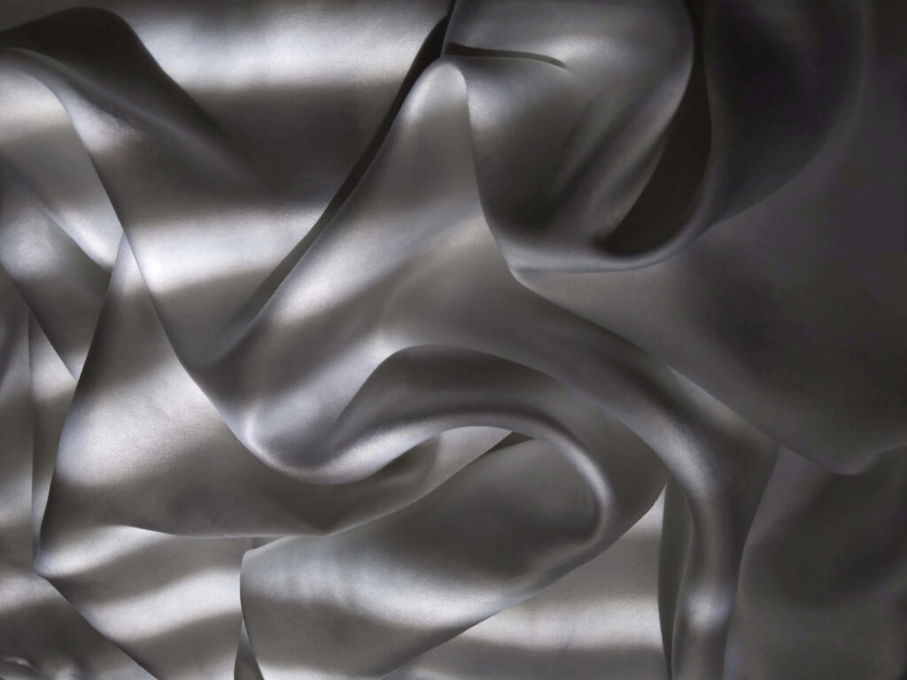 Serenity in Sunlit Silk: Captivating Background Photo with Gray Silk Fabric Illuminated by Sunbeam Wallpaper